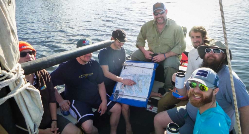 a group of veterans use a map to navigate on a sailing expedition 